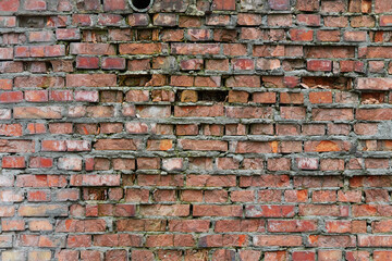 Old and broken brick, a sample of a brick wall in various shades of red, gray, orange and beige, sometimes covered with greenish mold. Wall texture and background for vintage wallpaper. 