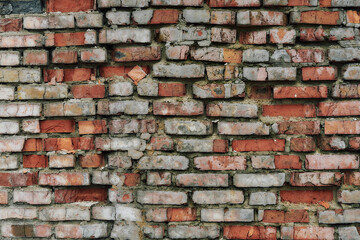 Old and broken brick, a sample of a brick wall in various shades of red, gray, orange and beige, sometimes covered with greenish mold. Wall texture and background for vintage wallpaper. 