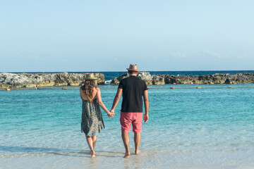 Fototapeta na wymiar Groom and bride walking in the Mexican Caribbean Sea