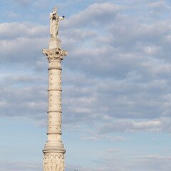 The Yorktown Victory Monument in Yorktown, Virginia, with a cloudy sky at sunset. There are birds...