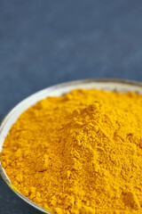 Close up picture of turmeric powder in a bowl, shallow depth of field, space for text.