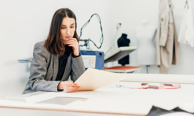 Horizontal image of a owner fashion female designer looking on the sketch for new collection. Businesswoman working on a new garment for an online store in her creative office.