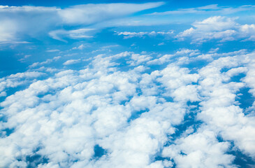 Naklejka na ściany i meble Cumulus white clouds and blue sky from the height of an airplane.