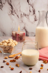 Milk bottle with glass and fiber cereals and nuts, on a marble tabletop and squared napkin, healthy and healthy breakfast and snack.