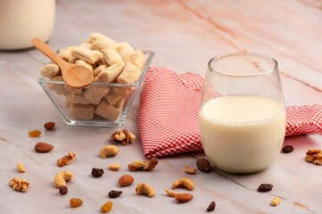 Milk bottle with glass and fiber cereals and nuts, on a marble tabletop and squared napkin, healthy...
