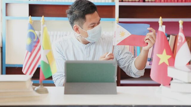 A young teacher wearing a mask teaches online the flag of the Philippines. Online teaching ideas during detention and safe distances from COVID 19