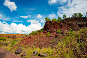 the prehistoric volcano that is extinct and the reddish stones are in contrast with the green grass - 434333800
