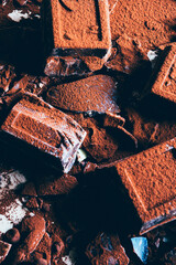 Chocolate bar pieces. A large bar of chocolate on gray abstract background. Slices of chocolate Sweet food photo concept, Chopped up chocolate for making Lava Cake.