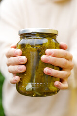 Woman housewife hand holding glass jar of pickled cucumbers. Domestic preparation pickling and canning of vegetables, winter organic food. Healthy fermented homemade food marinated cucumbers in jar.