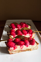 Raspberries rectangular shaped tart on a moody composition, with dark background,