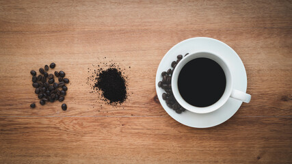 cup of coffee and coffee beans in a sack on Brown background, top view
