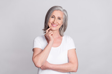 Photo of sweet thoughtful mature lady wear white clothes finger chin smiling isolated grey color...