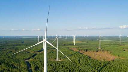 Aerial view of windmills in green summer forest close up. Wind turbines for electric power with...