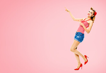 Full body portrait - amazed happy woman pointing at something. Excited girl in pin up style,...