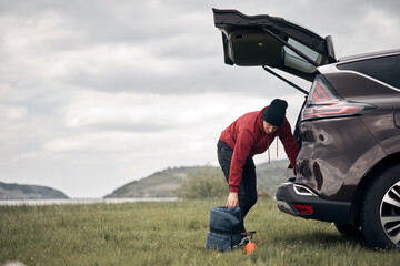Camper packing and unpacking from a car's back door in nature.