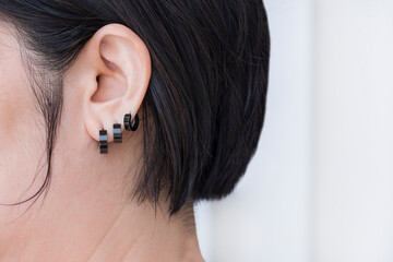 Close up and side view of Bob hair woman wearing 3 black stainless steel earrings on white...