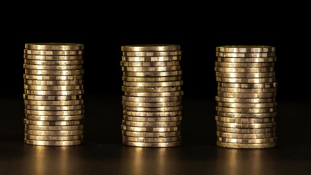 4K Stop motion shows the stack of three piles of gold cash coins decreasing and increase fading disappear from below with Key frame technique at black background, business and financial trading 
conce