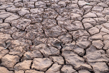 The cracked soil in the dry season indicates a heavy drought problem from nature.