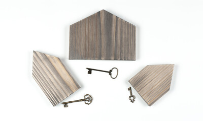 Miniature wooden house model. Construction buying a home loan. Old antique retro keys on a white background.