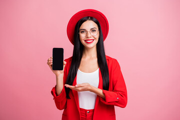 Photo portrait of girl demonstrating with hand phone with blank space isolated on pastel pink...