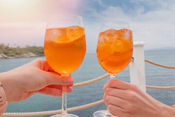 Two hands holding drinks over the sea