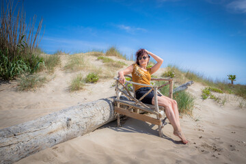 Fototapeta na wymiar Femme sur un banc en bois floté sur la plage du centre naturiste du Cap d'Agde