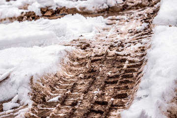 Wheel tracks on mud and snow. Snow on dirty soil with car wheel tracks. Dirty melting snow on the road.