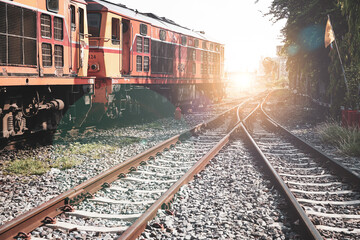 Fototapeta premium Railroad against beautiful sky at sunset. Train junction, Industrial landscape with railway station, colorful blue sky, trees and grass, yellow sunlight. Railway junction. Heavy industry. Railways. 
