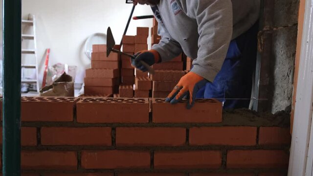 Construction worker building a brick wall. Man bricklaying. Mason laying bricks.