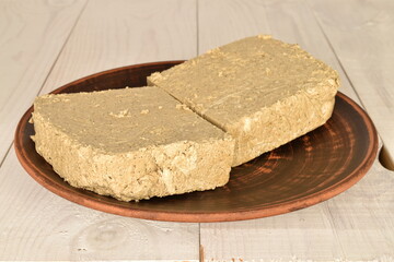 Two slices of vanilla halva on a clay plate, close-up, on a wooden table.