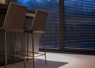 Wood blinds black color on large windows in the interior. Next to the window is a table with...