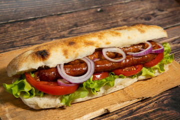 Sausages with salad served in bread on wooden board