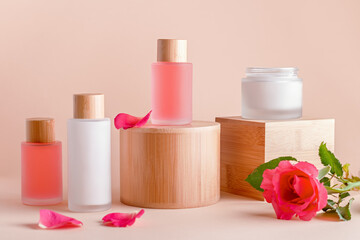 Obraz na płótnie Canvas Facial serum and cream with rose extract on wooden podiums