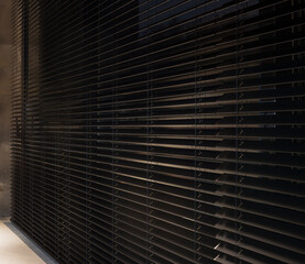Motorized wood blinds dark color in the interior. Automatic blinds closeup on the large windows. Coulisse wooden slats 50mm wide. Venetian blinds closed in the living room. 