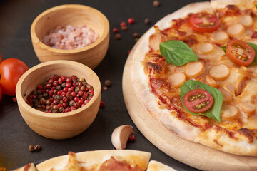 Italian pizza and pizza cooking ingredients on black concrete background. Tomatoes on vine, mozzarella, black olives, herbs and spices. Mixture pizza Italian food. Copy Space. Top view.