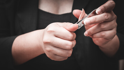 The hand of a white woman cutting her fingernails with nail clippers. Concept of hygiene.