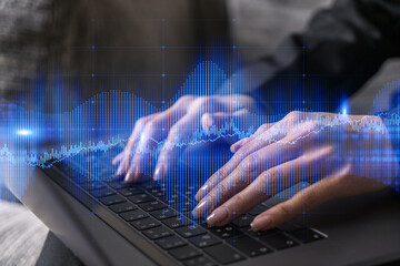 Businesswoman typing on computer in office. Fiancial graph hologram. Double exposure.