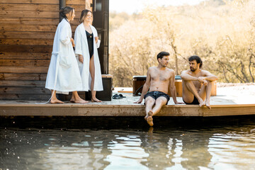 Company of friends rest on the terrace near the lake in the spa complex. Relax and fun time in...