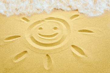 smiling sun face drawn in sand on the beach, summer beach holidays