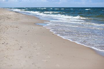 Sandy beach with pebbles on the sand in a sunny day. Baltic Sea.