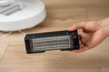 Male hands take out a dirty HEPA filter from a robot vacuum cleaner after cleaning