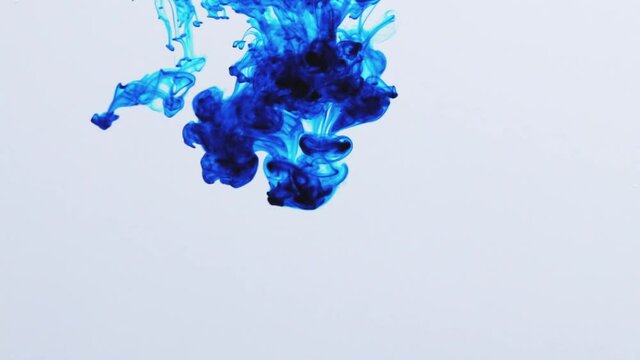 Blaue Inkjet Farbe fliesst ins Wasser im Gegenlicht.