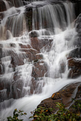 Fototapeta na wymiar Water delicately falls over bolders in Connestee Falls in Pisgah Forest
