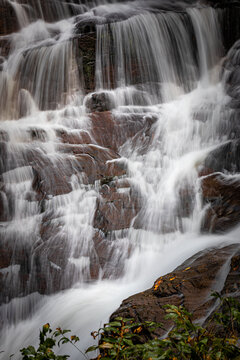 Water delicately falls over bolders in Connestee Falls in Pisgah Forest