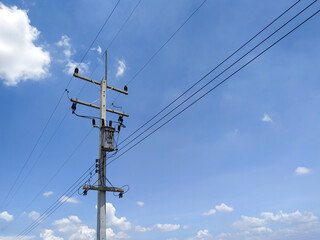 Cement high voltage pole with blue sky and white clouds copy space.