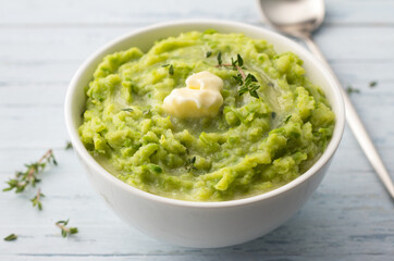 Delicate mashed potatoes with green peas, flavored with butter, spices and thyme on a light blue background. delicious homemade food