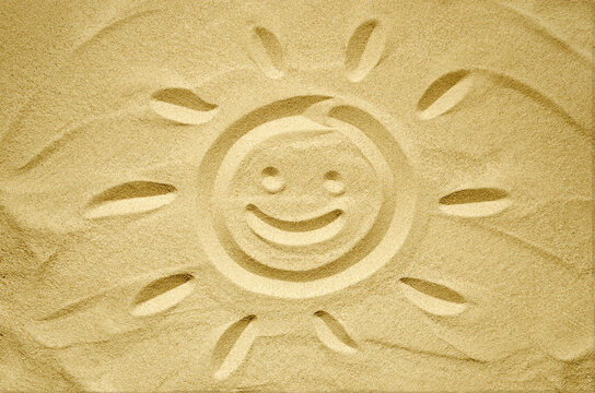  face of smiling sun drawn in sand, summer beach holidays