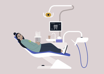 A dentist chair and tools, a monitor with an x-ray image, drills and other instruments in a stomatology cabinet