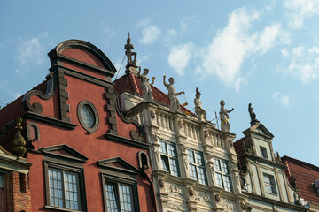 A close up of the facades of tall building in the middle of Old Town in Gdansk, Poland. The buildings have many bright colors, they are richly decorated. City tour. Clear day.