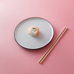 sushi roll Philadelphia on a plate on a pink background. Delicious fresh roll with curd cheese,...